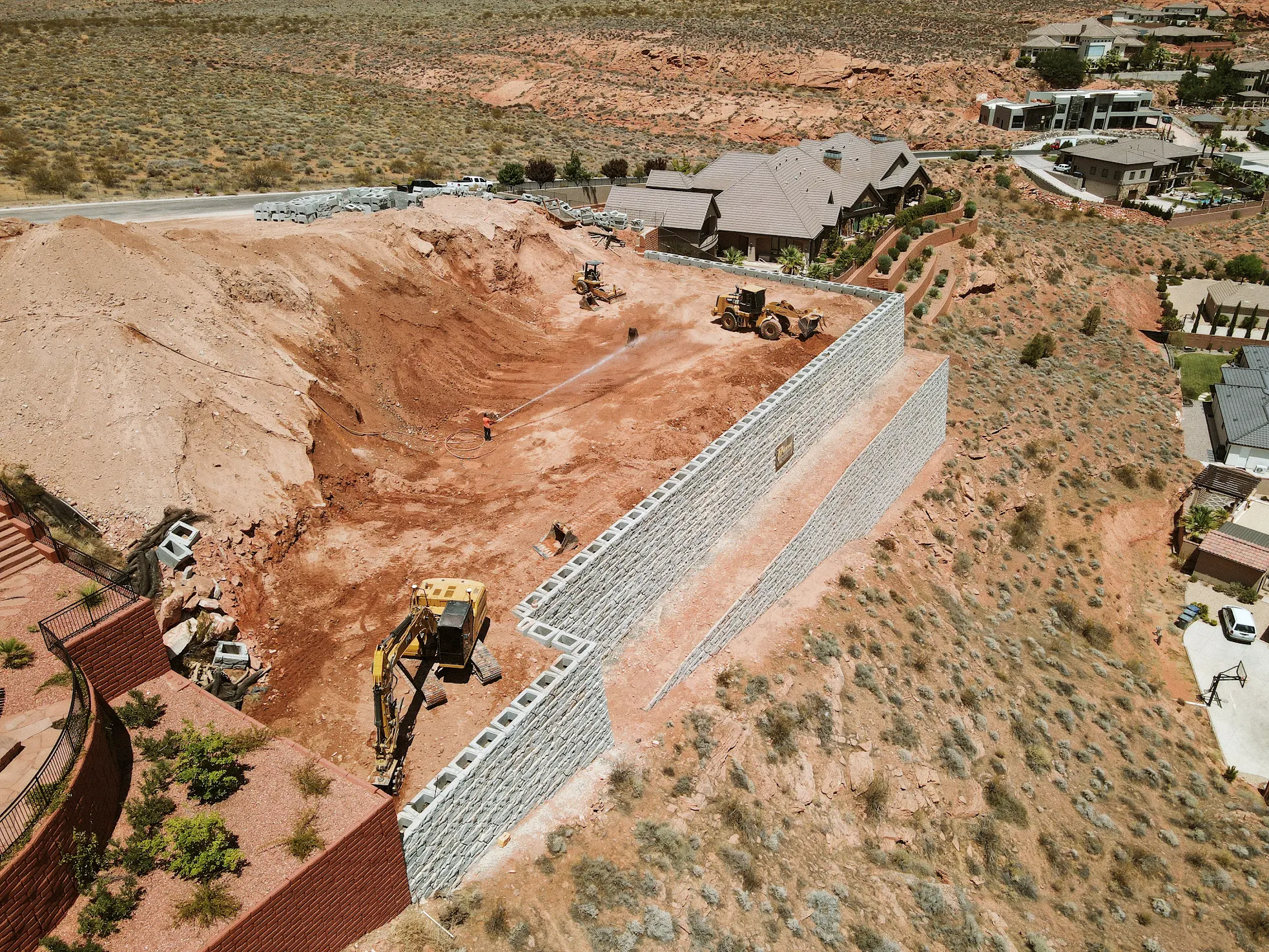 Precast block retaining wall construction in St. George, Utah with excavation equipment